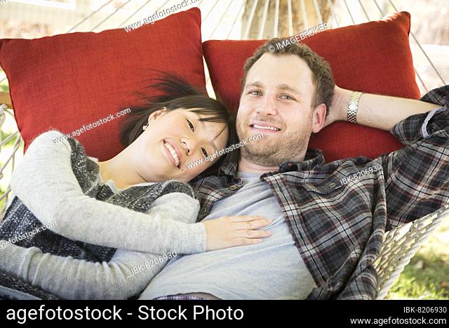 Happy mixed-race couple relaxing in a hammock outside