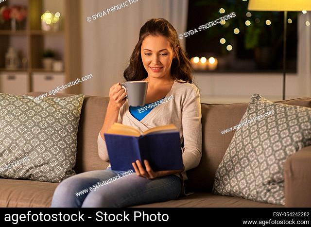 young woman reading book at home in evening