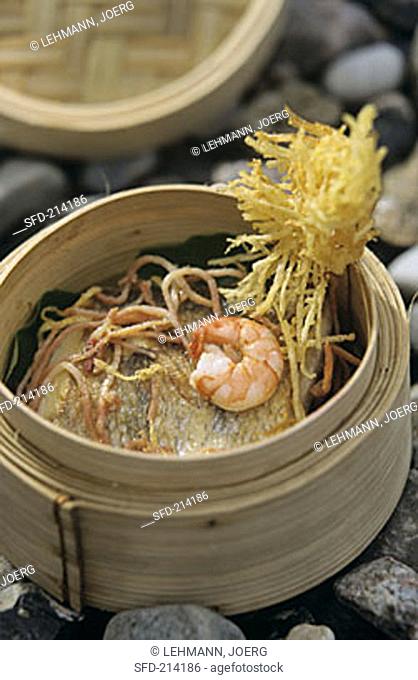 Scampi on pike-perch in bamboo steamer on stone background