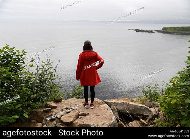 RUSSIA, SAKHALIN REGION - JULY 19, 2023: A woman enjoys a panoramic view of the coast near the Wall of Waterfalls (Weeping Rocks) on Iturup