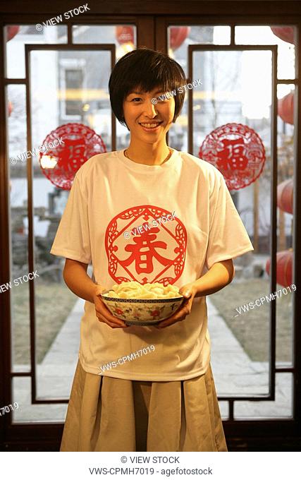 Chinese young woman holding a bowl of Chinese dumpling