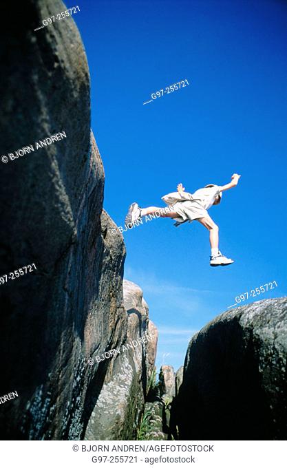 Boy jumping over abyss