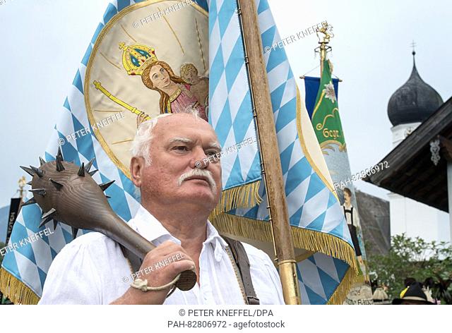 A man miming the historical 'Blacksmith of Kochel' carrying a flag of Maria during the traditional costume parade on Assumption Day in Kochel am See, Germany