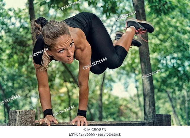 Female athlete jumping over wooden barrier on fitness trail