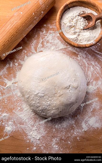 Homemade yeast dough freshly prepared for pizza or bread on wooden background.. Home cooking concept