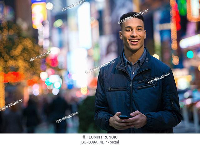 Young male tourist on busy street, New York City, USA