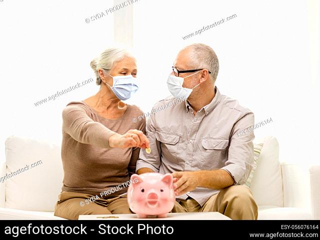 old couple in masks putting coin into piggy bank