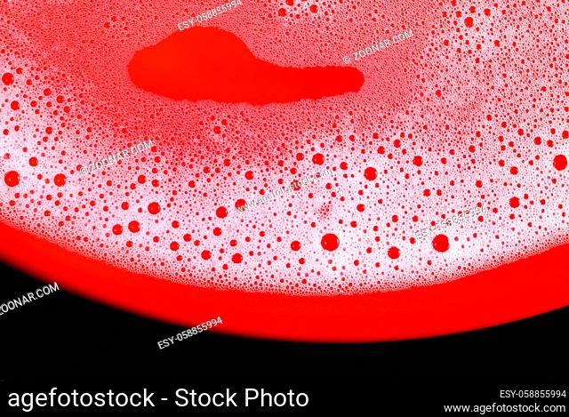 Soap sud on red background. Detergent concept. Foam with bubbles. Shampoo in water. Flat lay