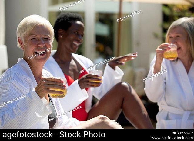 Happy senior woman enjoying cocktail with friends on sunny hotel patio