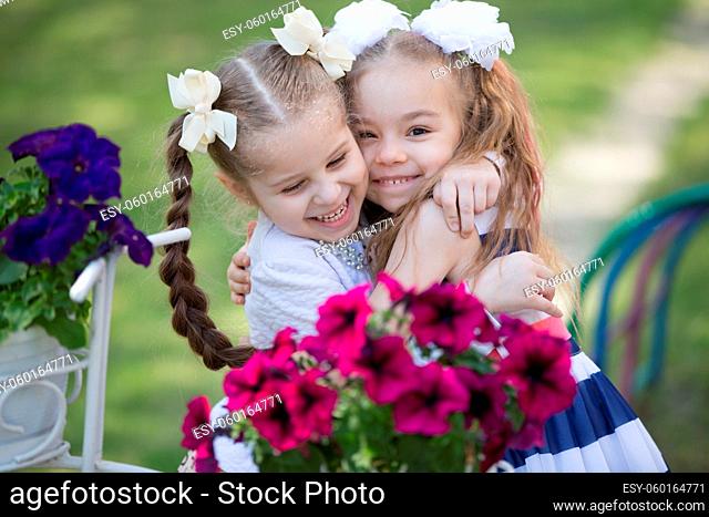 Two little six-year-old girlfriends embrace against a background of bright colors. Children's friendship