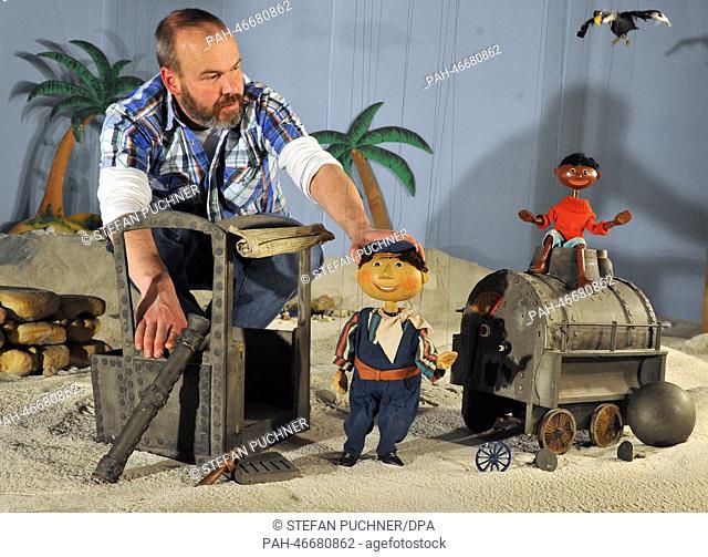 Hans Kautzmann sits with marionettes Lukas (L) and Jim Knopf as well as broken locomotive Emma in a desert scenario at the Puppenkiste (puppet chest) museum in...