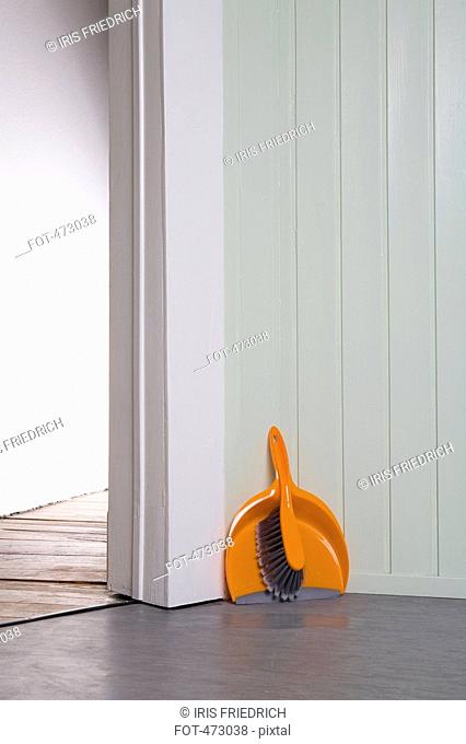 A dustpan and broom in a corner