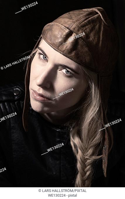 Young beautiful blonde woman in retro leather cap. Showing expression of cool attitude and personality