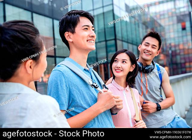 Outdoor four college students against the fence chatting together