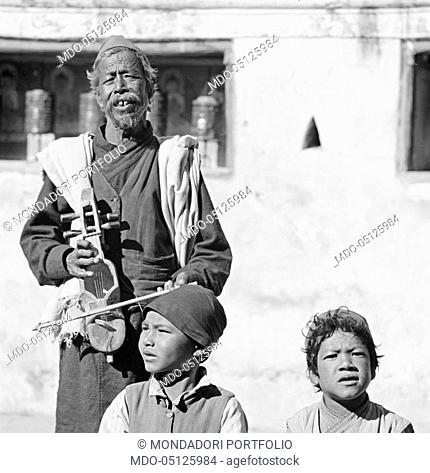 Nepalese man playing the sarangi beside two boys. Nepal, 1965