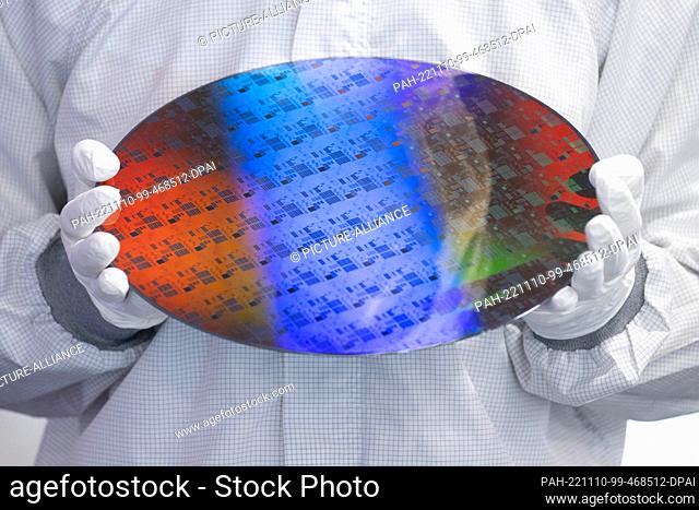 10 November 2022, Saxony, Dresden: An employee of the chip manufacturer Globalfoundries holds a wafer on the sidelines of a press conference on the balance on...