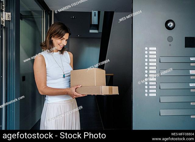 Smiling woman looking at packages standing at door