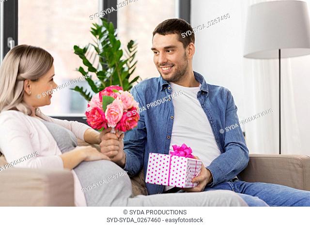 man giving flowers to pregnant woman at home