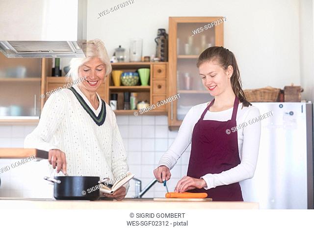 Mother and adult daughter cooking together at home