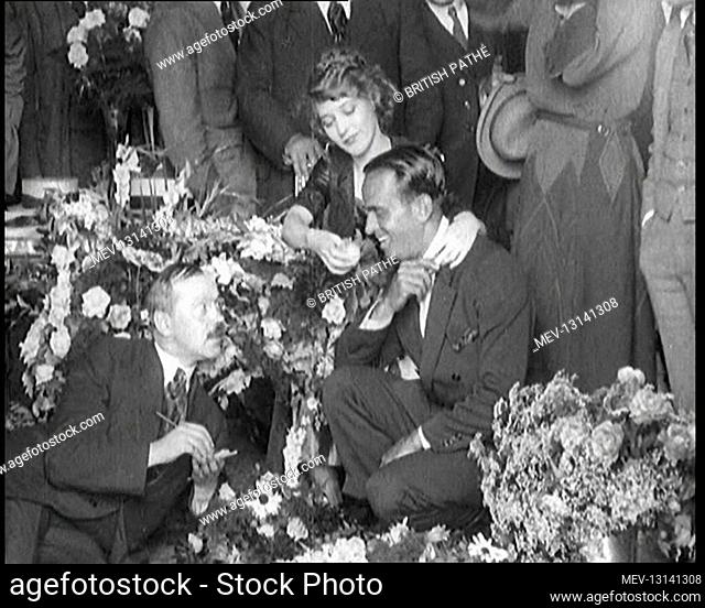 Mary Pickford and Douglas Fairbanks Senior Sitting Together Amongst A Bed Of Flowers In Paris. Mary Is Offering A Piece OF Fruit To Douglas - Paris