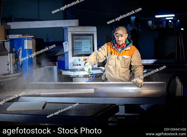 A furniture production worker behind a programmed machine makes furniture parts. Furniture manufacturing