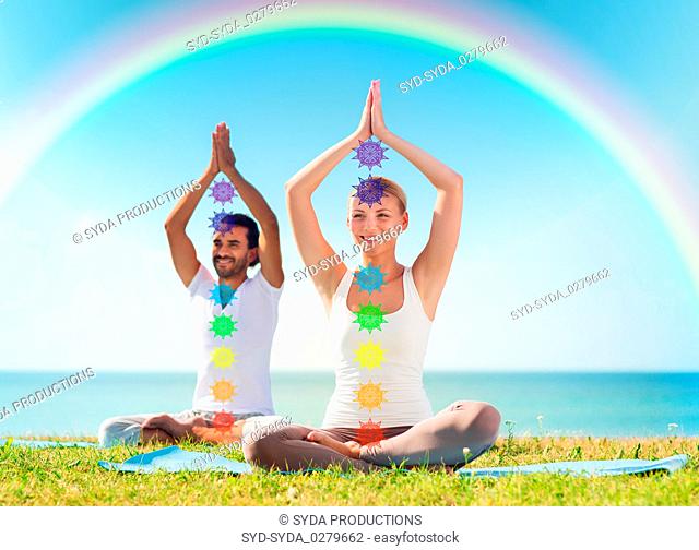 couple doing yoga in lotus pose with seven chakras