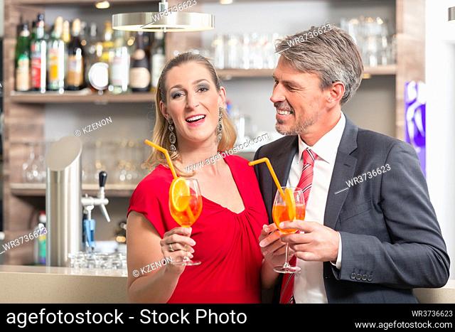 Happy mid adult couple holding cocktail at bar