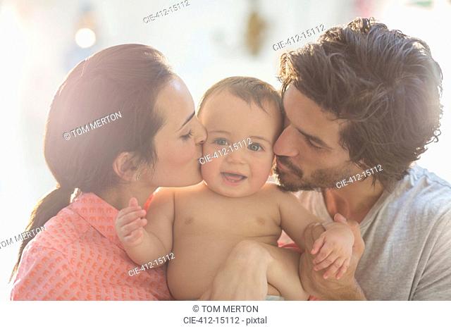 Parents kissing baby boy's cheeks