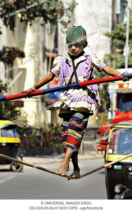 South Asian Girl Working Street Performer Balancing Act By Walking On Rope With Bamboo In Hand