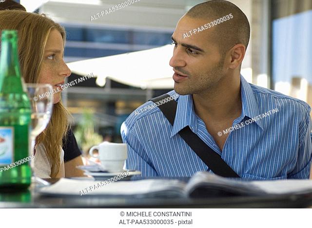 Man and woman sitting in outdoor cafe, having serious conversation