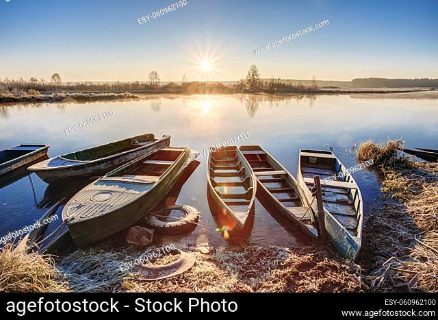 River and old rowing fishing boats at beautiful sunrise sunset in autumn morning. Lens flare effect