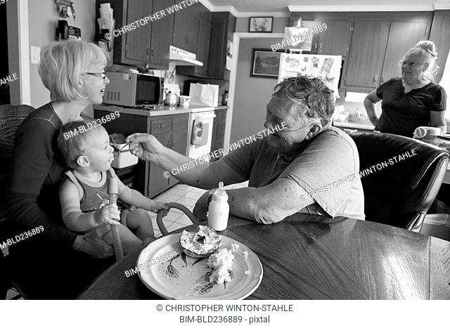 Caucasian grandfather feeding grandson in kitchen