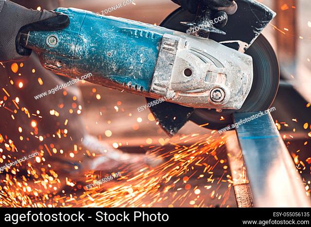 Construction worker using Angle Grinder cutting Metal at construction site