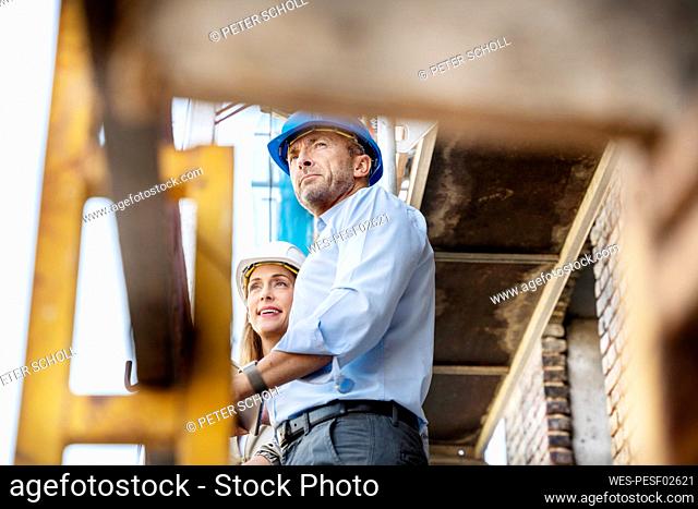 Architect looking away while standing by colleague at construction site