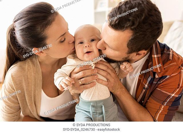 happy mother and father kissing baby at home