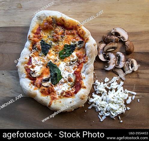 Napolitano Pizza with mushrooms and mozzarella on wood cutting board