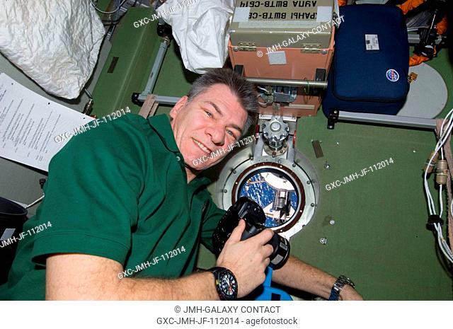European Space Agency astronaut Paolo Nespoli, Expedition 26 flight engineer, uses a still camera at a window in the Zvezda Service Module of the International...