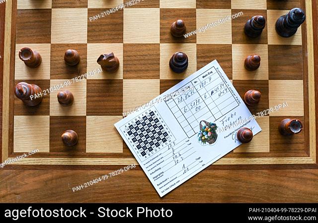 01 April 2021, Berlin: In the apartment of chess player Heiermann, who plays correspondence chess by mail, there is a postcard on a chess board with the chess...