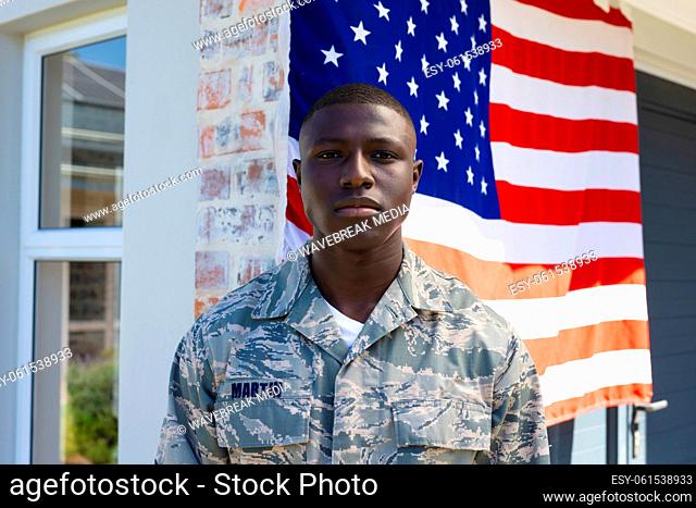 Portrait of african american mid adult army soldier in camouflage clothing standing against flag