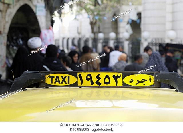 Close up of a taxi sign on the roof of a yellow taxi, standing in a crowd of people, seen in the background, Damascus, Syria, Near East, Asia