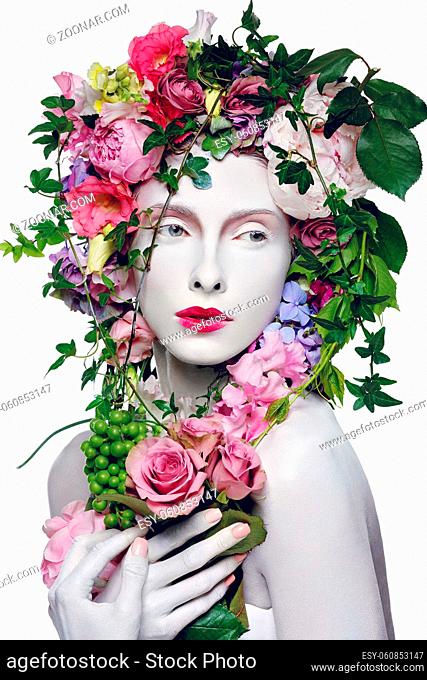 Beautiful young pale white woman with different flowers on head. Flower queen. Beauty shot isolated on white background