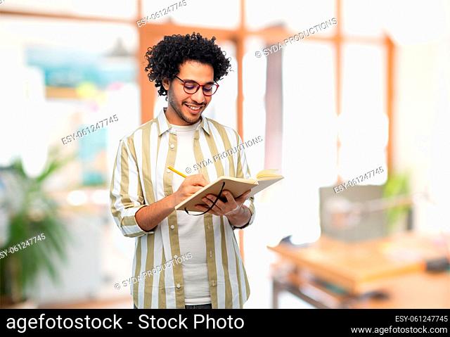 smiling young man with diary and pencil at office