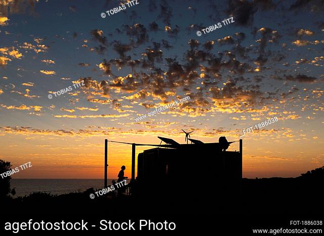 Clouds in dramatic sunset sky over silhouetted beach shack, Adelaide, Australia