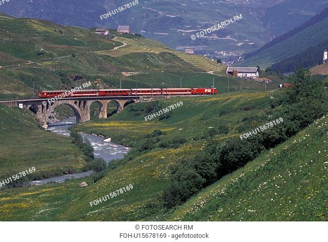 train, Switzerland, Uri, Urseren, Alps, The red Glacier Express Train travels through the scenic valley near the village of Hospental in the Swiss Alps