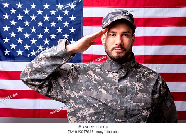 Portrait Of A Male Solider Saluting Against The American Flag