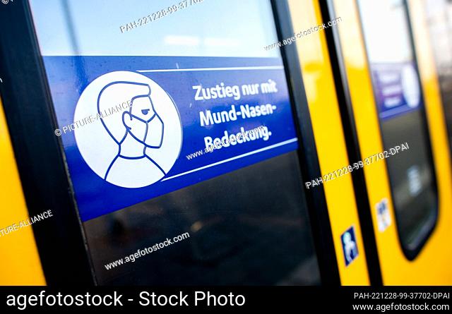 12 December 2022, Lower Saxony, Oldenburg: A sign with the inscription ""Boarding only with mouth-to-nose covering."" is stuck on the train door of a...