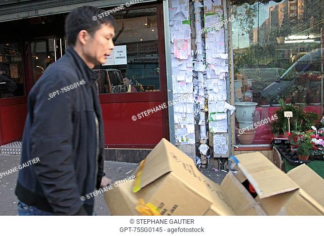 ASIAN DELIVERYMAN, DAZIBAO, POSTING OF ADS AND NOTICES ON THE WALLS IN THE CHINESE NEIGHBOURHOOD, RUE DE BELLEVILLE, PARIS 75, 20TH ARRONDISSEMENT