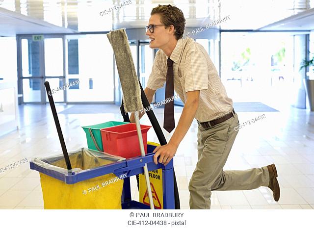 Businessman pushing cleaning cart in office
