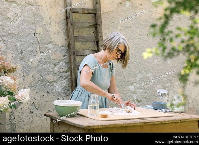 Mature woman preparing dough at back yard