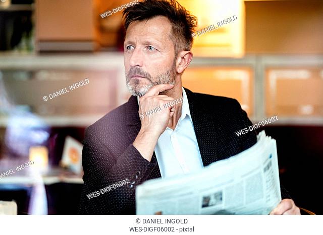 Portrait of pensive mature businessman with newspaper in a coffee shop